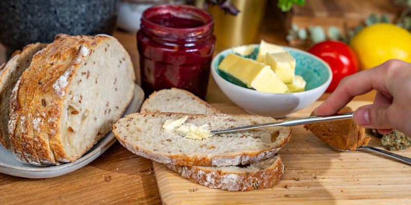 Skär två tjocka skivor cannabisbröd med brödkniven på skärbrädan Cut Two Thick Slices Of Cannabis Bread Using The Bread Knife And Chopping Board