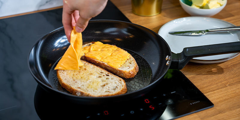 Lägg en brödskiva i pannan med den vanliga smörsidan nedåt. Lägg ostskivorna ovanpå brödet Lägg en brödskiva i pannan med den vanliga smörsidan nedåt. Lägg ostskivorna ovanpå brödet