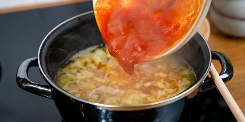 Tillsätt tomaterna eller tomatpurén och grönsaksbuljongen; sänk värmen och låt sjuda Tillsätt tomaterna eller tomatpurén och grönsaksbuljongen; sänk värmen och låt sjuda
