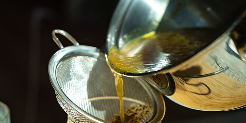 Sila blandningen ner i en annan behållare för att få bort växtmaterialet Strain The Mixture Into Another Container To Remove The Plant Matter