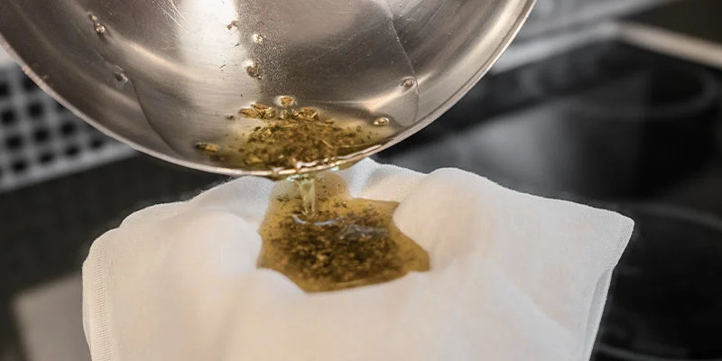 Sila bort allt växtmaterial med en silduk eller finmaskig sil, eftersom THC nu har extraherats. Use a cheesecloth or fine strainer to remove all plant material, as the THC will now have been extracted.